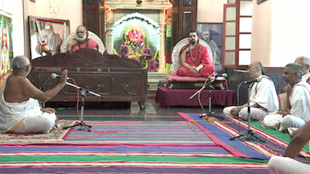 S.L.P. Anjaneya Sarma (left) adressing the learned assembly in Shringeri: Bhāratītīrtha-mahāsvāmi, Vidhuśekhara-Bhāratīsvāmi, Maṇidrāviḍa-śāstrigaḷ, Nāgarājabhaṭṭa, etc.